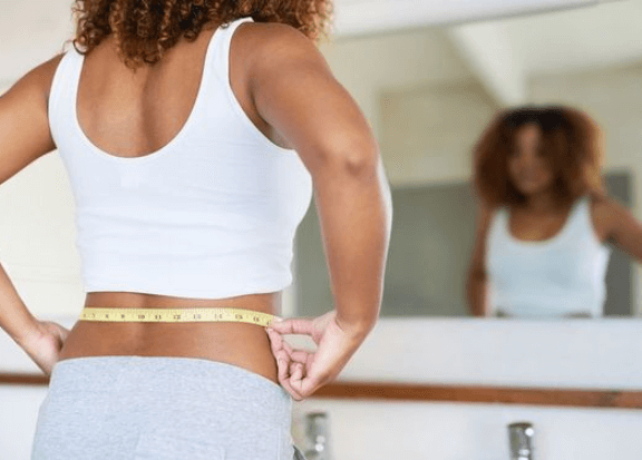 A Woman Measuring Her body against the Mirror